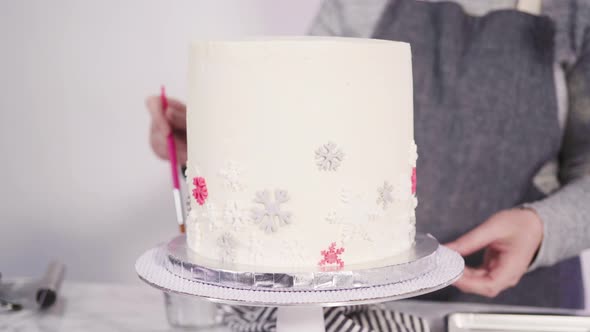 Step by step. Decorating round funfetti cake with pink and white fondant snowflakes.