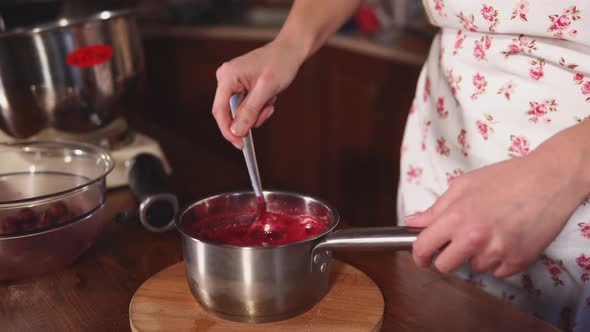 Pastry Chef Is Mixing Red Berry Sauce in a Bowl on Kitchen Table