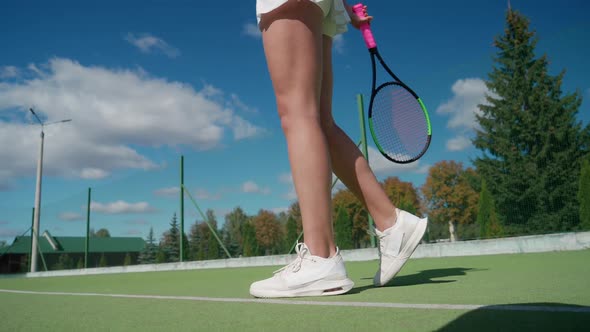 Anonymous Female Tennis Player Hits a Ball Off the Floor in a Outdoor Court Low Angle View of the