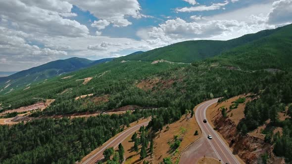 Aerial video of the road through dense green forest on mountain slopes in Wyoming, USA