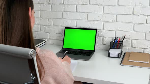 Woman student at home sits table study greets writes information in notebook