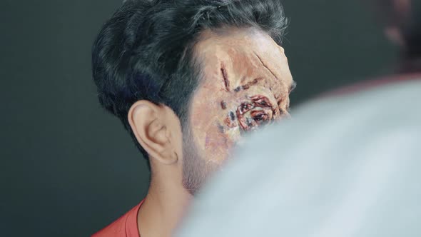 Man with prosthetic Halloween mask on his eye in cosmetics studio