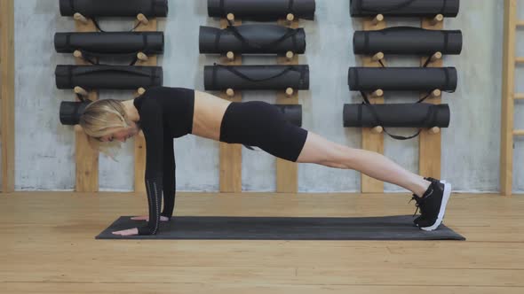 Fitness woman doing plank exercise workout in gym indoors, girl doing cardio moves her legs