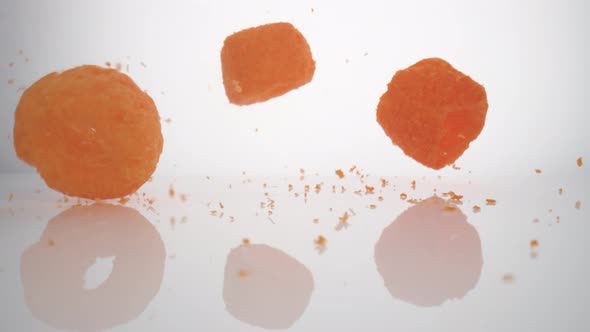 Camera follows cheese puffs falling on surface. Slow Motion.