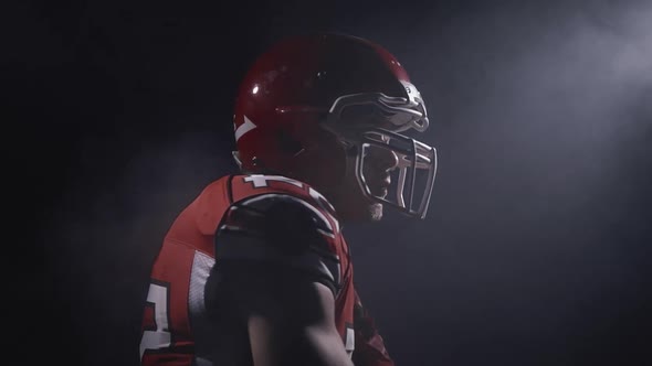 Portrait of Determined Professional American Football Player in Helmet in Dramatic Light Ready for