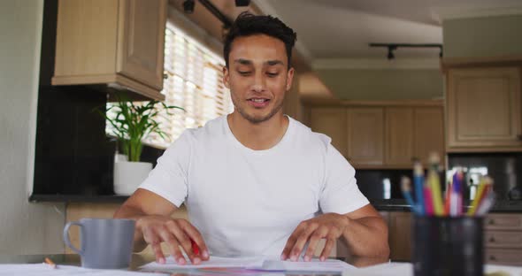 Happy latin man gesturing and having video call in kitchen