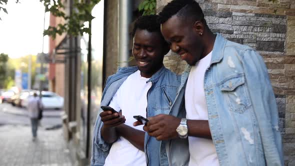 Smiling African Men Looking Photos in Their Smartphones