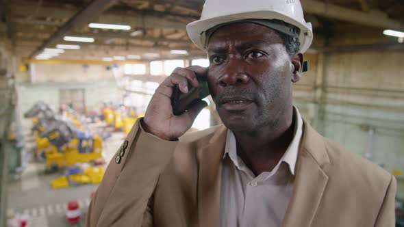 African American Engineer Speaking on Mobile Phone in Factory