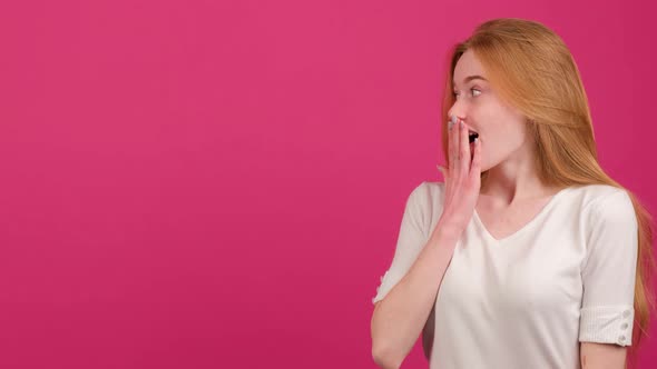 Woman Shocked By Something Covers Her Mouth with Her Hand and Points to the Left