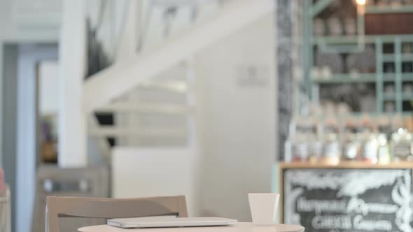 Young Woman Coming Back Opening Laptop in Cafe