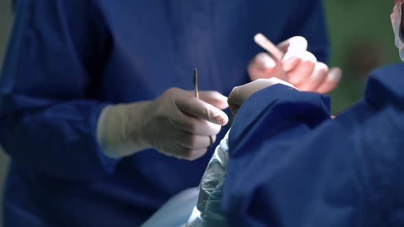 Hands of Surgeon and Nurse with Operating Instruments Doing Operation in Surgery Room