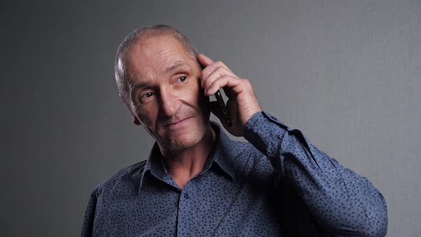 Elderly Man Communicates Via Smartphone on Grey Background