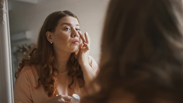 Close Up Shot of Young Plus Size Lady Applying Toner on Face Looking at Mirror at Home