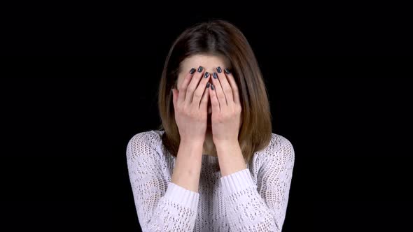 The Young Woman Shows Emotions of Sadness on Her Face. Woman Cries and Covers Her Face with Hands