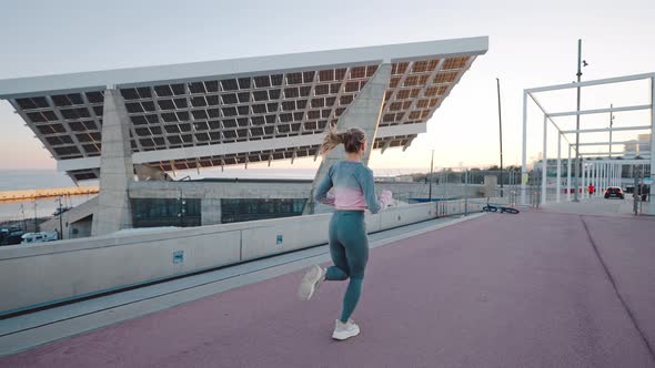 Energetic Young Female Jogger Running By Bridge in Urban Area