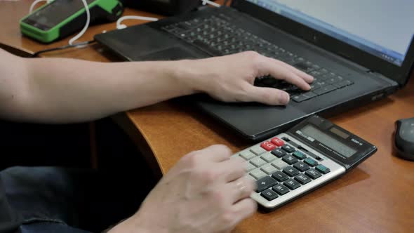 The Accountant at Home at the Computer Counts the Numbers on the Calculator and Transfers the Amount