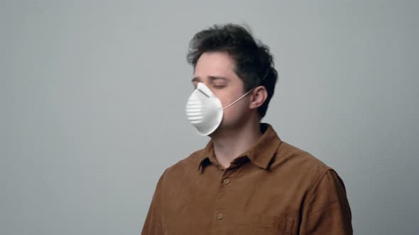 guy in a mask sneezes on a grey background