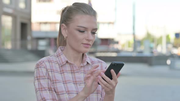 Young Woman Browsing Internet on Smartphone Outdoor