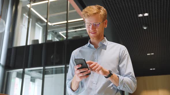 Middle Aged Businessman Use Smartphone Computer Apps for Work in Office