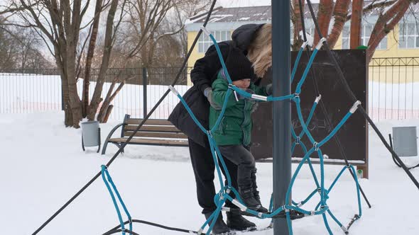 Mom Helps Little Son Climb the Ropes