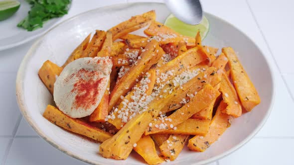 Baked sweet potato wedges with hummus, nuts and seeds in bowl.