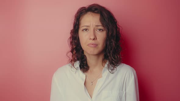 Young Attractive Girl Desperately Crying on a Pink Wall Background