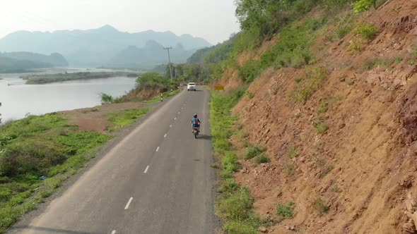 Aerial view of Motorcyclist on road next to Mekong River, Laos 