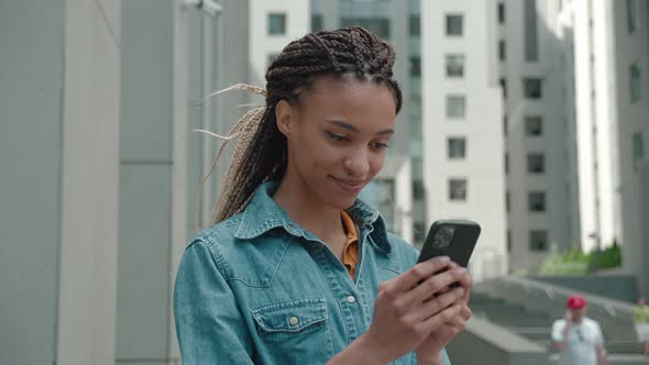 Mixed Race Girl Jacket Using Smart Phone Outdoors of the Business Center the Background