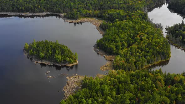 Early fall aerial footage of remote lake in northern Maine panning down towards island near shore