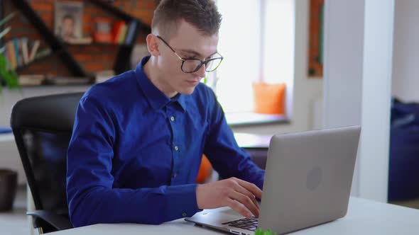 Young Worker in Startup Company Sitting at the White Desk