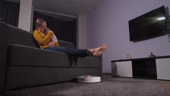 Happy Woman Petting Puppy While Robot Cleaning