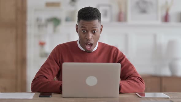 African Man Celebrating Success while using Laptop in Office