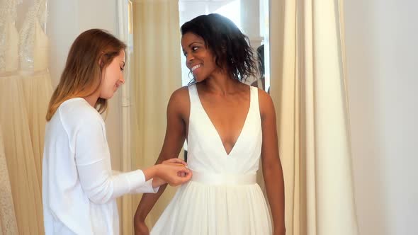 Woman trying on wedding dress with the assistance of fashion designer