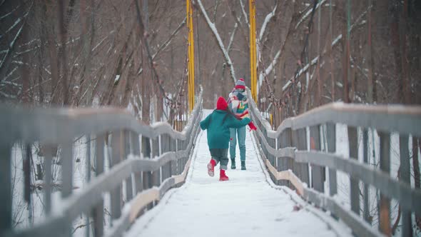 Two Young Women in Colorful Sweaters Having Fun on the Snowy Bridge