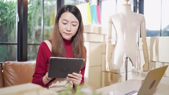 Asian female shop owner checking customer order on tablet