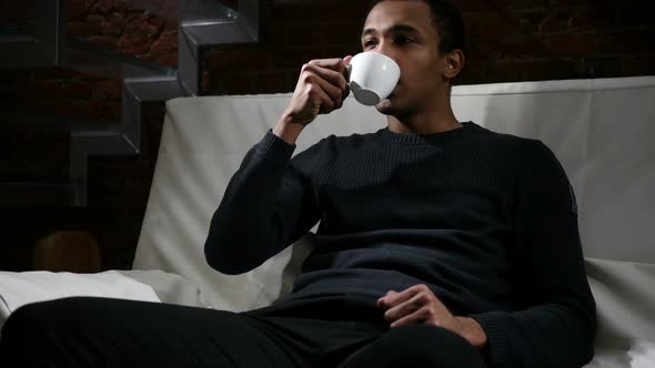 Pensive African Man Drinking Coffee From Cup Loft Interior