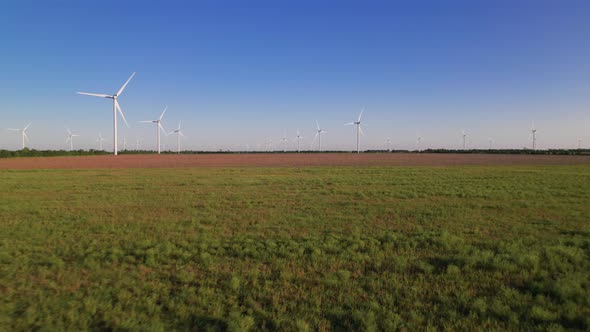 Windmills in a green field. Wind farm with turbine cables for wind energy.