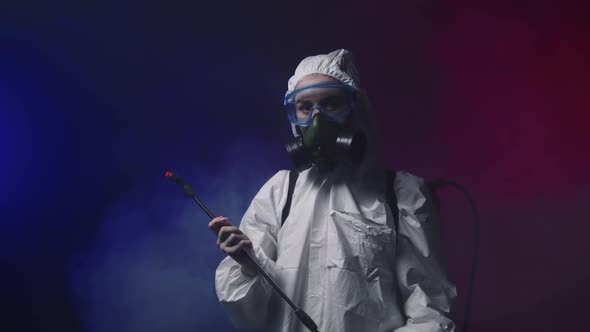 A Person in White Protective Medicine Suit Standing in Smoky Room Holding Cleaning Equipment and