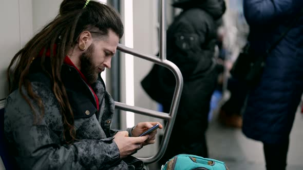 Young Man with Dreadlocks is Surfing Social Media Scrolling Screen of Modern Smartphone