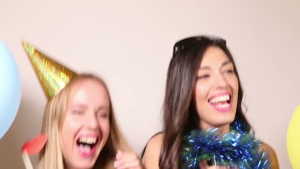 Close up of two beautiful women dancing and laughing in party photo booth