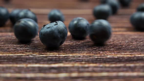 Fresh Organic Blueberries Rolling on the Dark Wooden Table, Closeup Side View