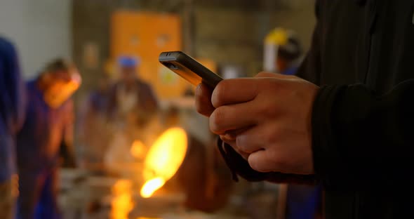 Male worker using mobile phone in workshop 4k