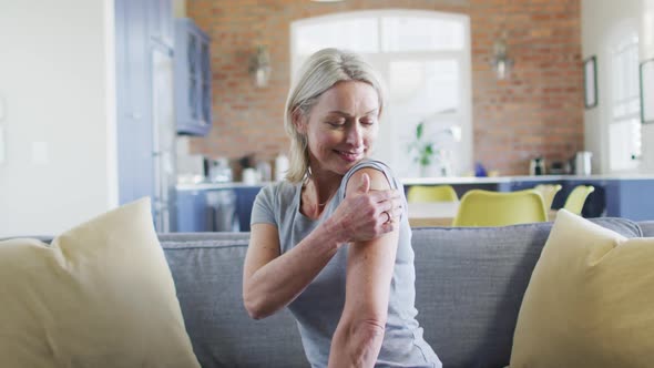 Portrait of happy senior caucasian woman in living room with bandage on her arm