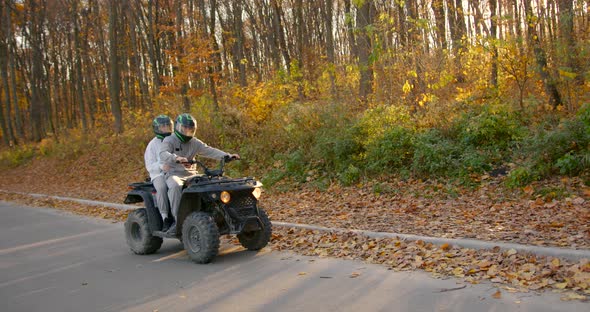 A Young Couple Rides an ATV Offroad in the Autumn Forest