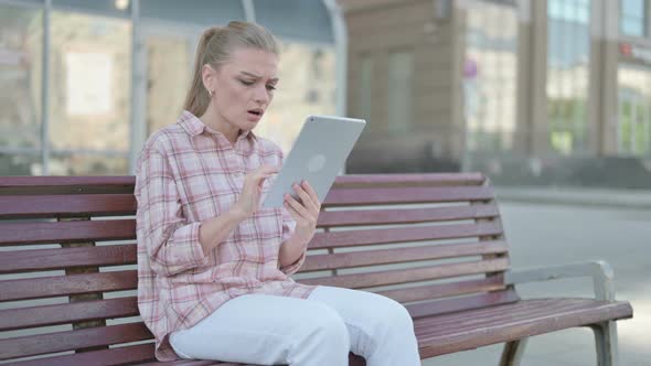Young Woman Reacting to Loss on Tablet While Sitting Outdoor on Bench