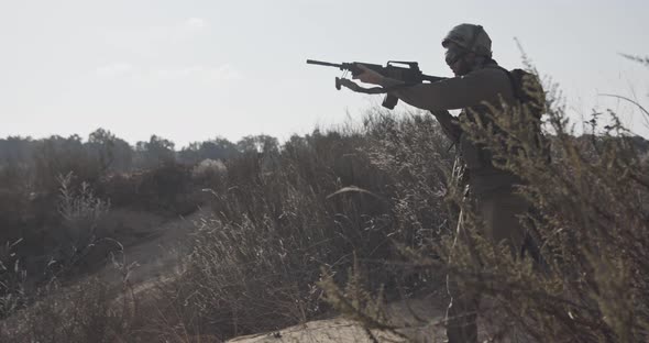 Slow motion of an israeli soldier walking with a rifle on a sand hill