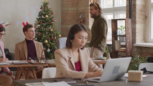 Manager Chatting with Colleagues Working in Office on Christmas