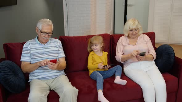 Senior Couple Grandparents with Child Girl Grandchildren Using Digital Tablet, Mobile Phone