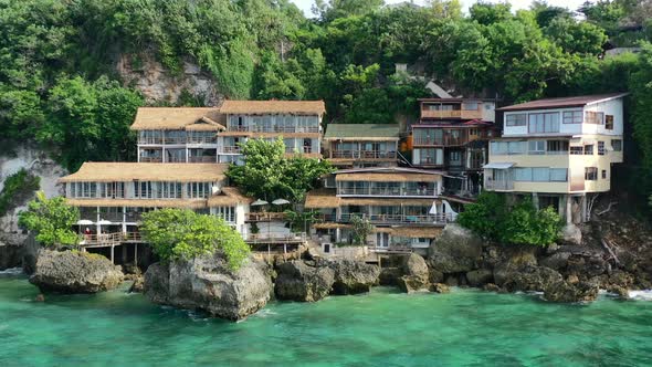 house on a large island cliff in Uluwatu Bali over tropical turquoise ocean, aerial