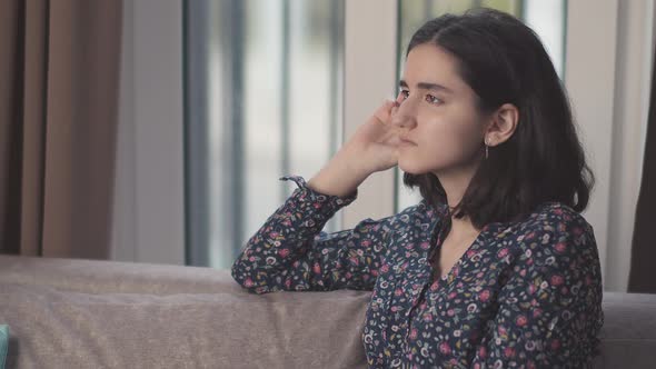 Brunette Girl Lost in Thought Sits on the Sofa